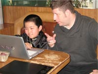 Perry Chen and Kevin Sean Michaels looking at a laptop screen, Kevin pointing, Perry mousing